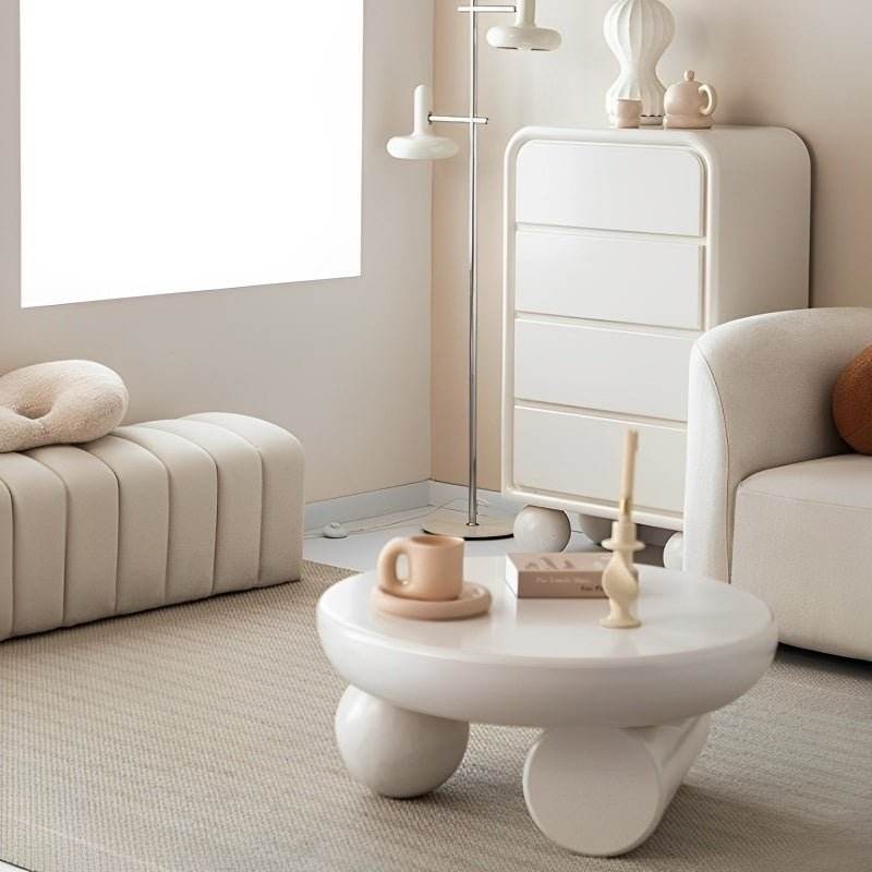 A round, white coffee table with a minimalistic design, placed in a modern living room setting.