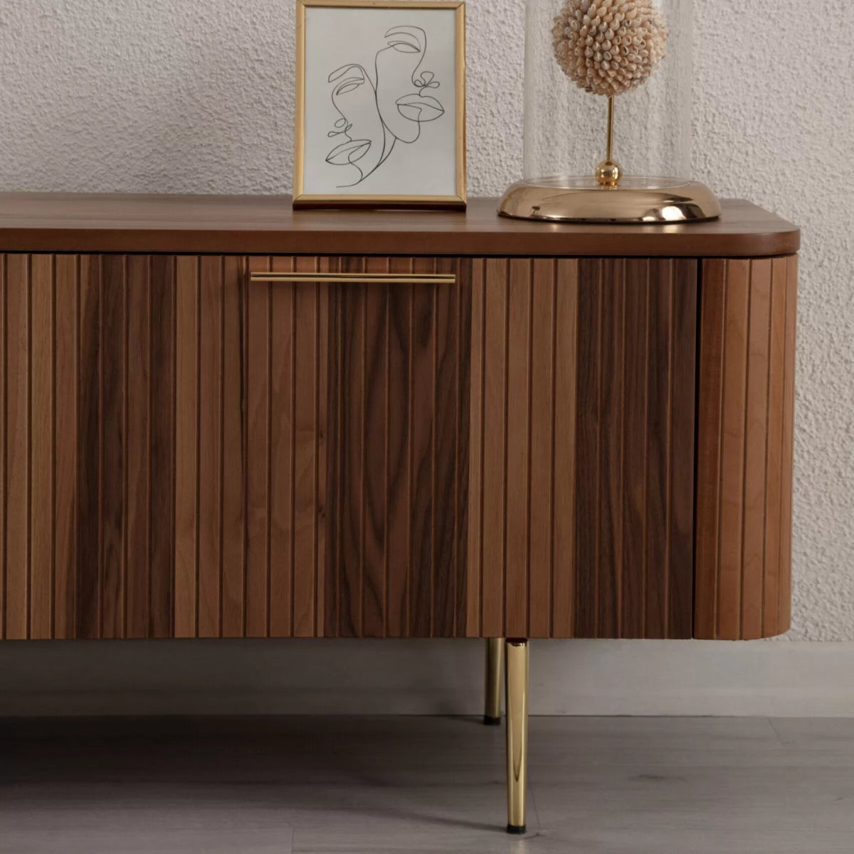 Asta Wooden Fire TV Unit 200cm. Close-up, straight-on view of the side cabinet of the TV unit, featuring rich brown walnut wood with vertical slatted paneling on the door. It includes a sleek brass handle and slender brass legs, highlighting the textured detail and premium materials for a stylish storage solution.