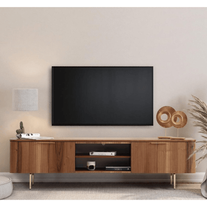Asta Wooden Tv Unit 200cm. Wide, contemporary wood media console featuring vertical slatted cabinet doors on both ends and open central shelving with two shelves, supported by short gold angled metal legs beneath a wall-mounted TV.