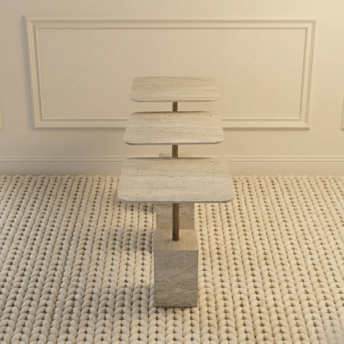 Travertine nesting tables on a textured rug against a wall with decorative molding.