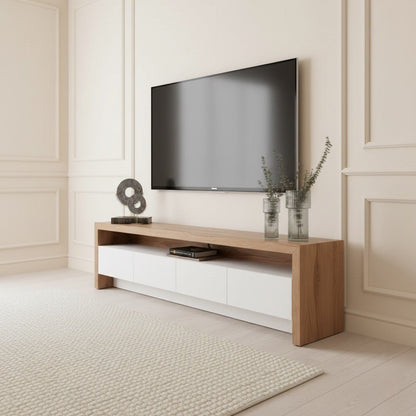 Dantone Tv Unit 200cm. Angled shot of the wide, contemporary media console with a light wood top and thick side panels, featuring four handleless white storage drawers below a central open shelf, placed beneath a mounted TV.