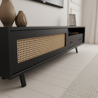 Finn Tv Unit black 200cm. Close-up detail of the black media console, highlighting the contrast of the printed woven rattan/cane-front sliding cabinet door and the black storage drawer with an open shelf, all supported by black angled legs.