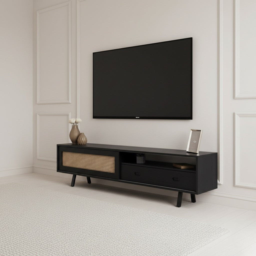 Finn Tv Unit black 200cm. Angled shot of the contemporary black media console featuring a printed woven rattan/cane-front sliding cabinet door on the left, an open shelf, and two drawers with black handles on the right, supported by black angled legs beneath a wall-mounted TV.