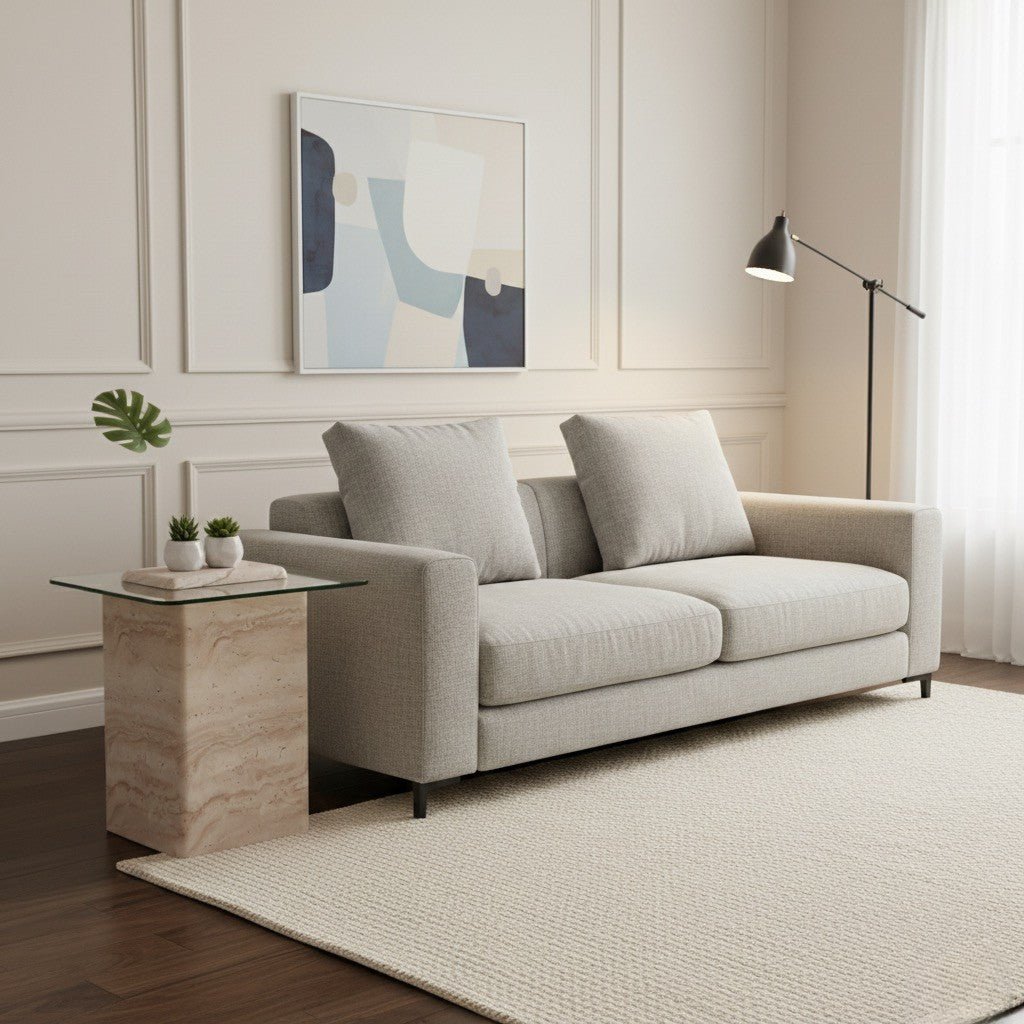 Modern living room with a gray sofa, travertine side table, and abstract art on the wall.