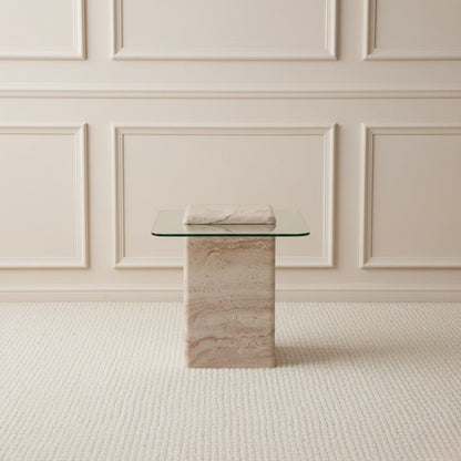 Glass table with travertine stone base against a beige paneled wall