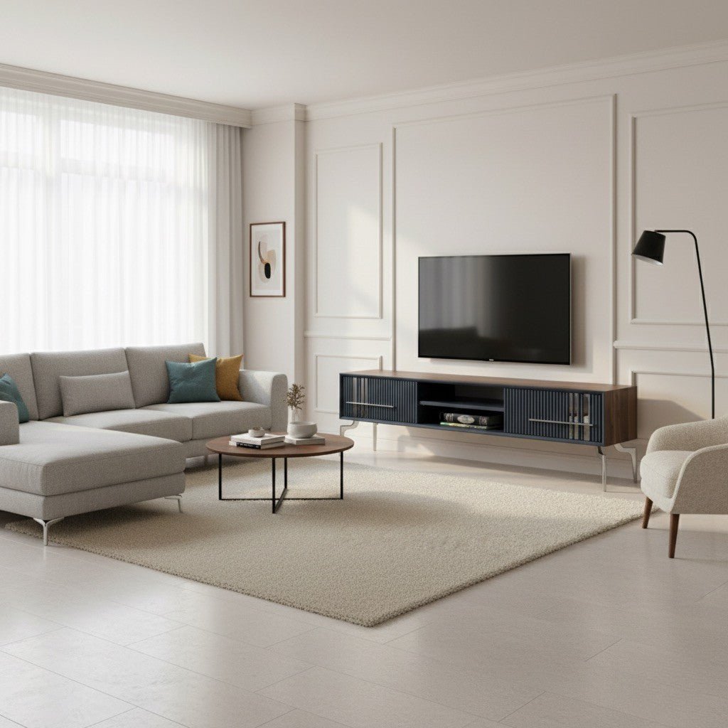 Lincoln Wooden Tv Unit Grey 200cm. Full view of a modern living room featuring the grey media console with ribbed cabinets and silver accents, positioned below a wall-mounted TV. The room also includes a light grey sectional sofa, a round wooden coffee table, and a cream accent chair.