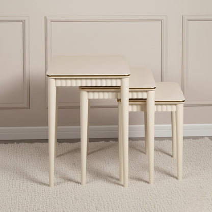 Set of three beige nesting tables against a neutral wall.