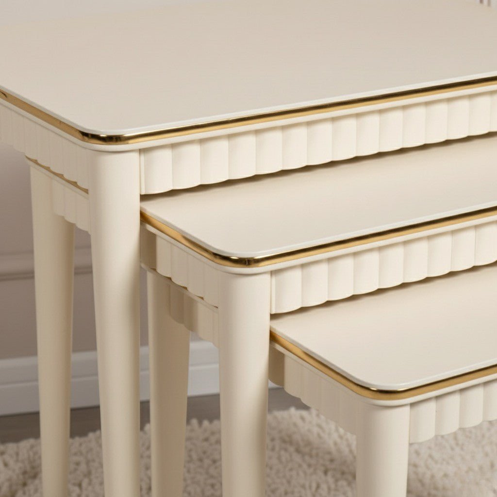 Set of three white nesting tables with gold edges on a neutral background