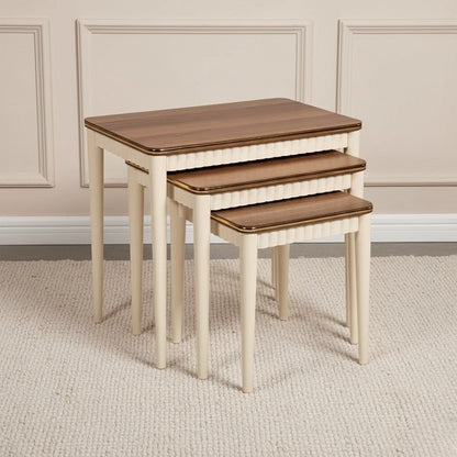 Set of three nested tables with wooden tops and off-white legs on a neutral background