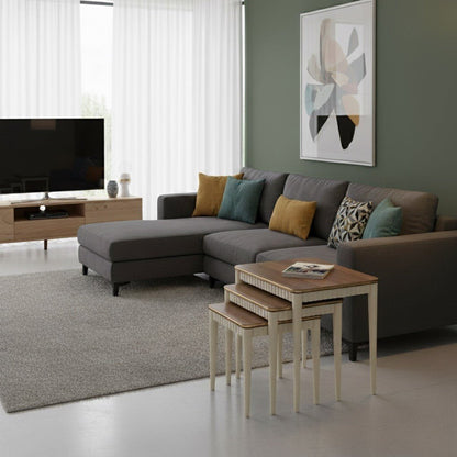 Modern living room with a gray sectional sofa, nesting tables, and abstract art on the wall.