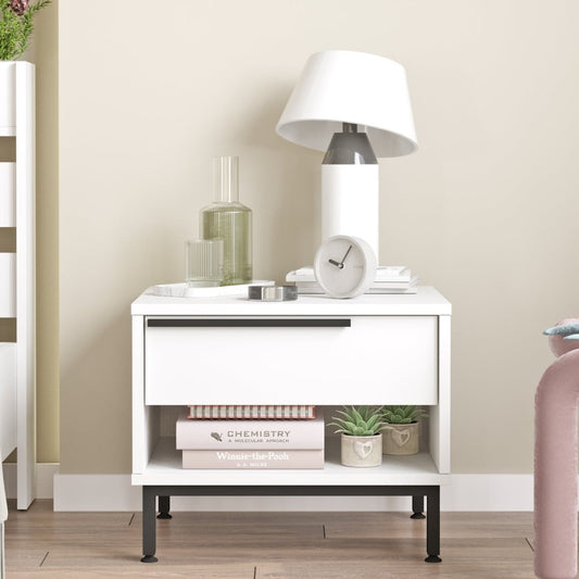 White nightstand with lamp, books, and decor items against a beige wall.