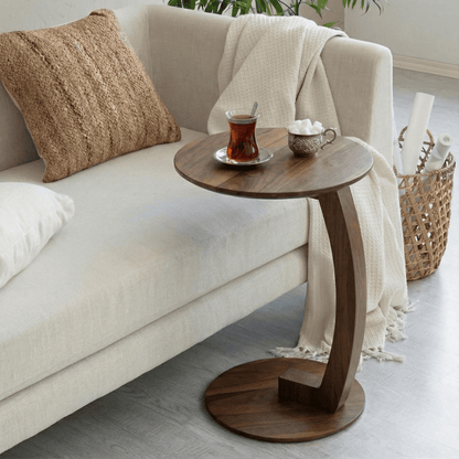 Wooden side table with tea set next to a beige sofa in a living room.