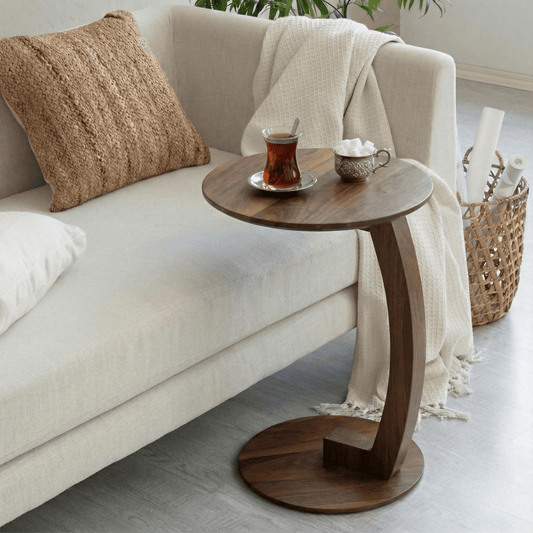 Wooden side table with tea set next to a beige sofa in a living room.