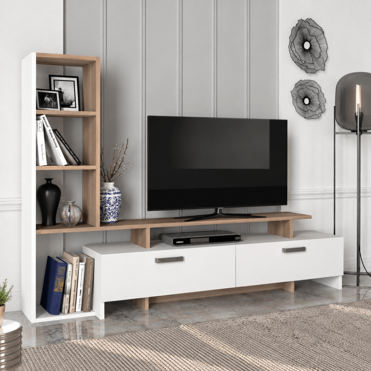 A modern white TV stand with light wood accents and open shelving, styled in a living room setting with a television, books, and decorative vases.