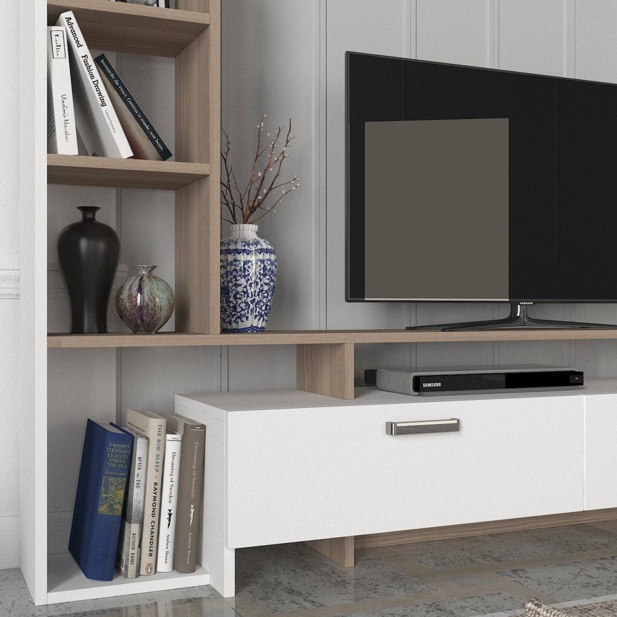 A modern media console with a white drawer unit and light wood open shelves, styled with books, vases, and a television against a white paneled wall.