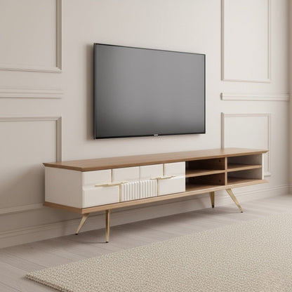 Tribe Wooden Tv Unit Cream 200cm. Angled shot of the wood and cream media console featuring four storage drawers with gold handles (one ribbed texture), four open cubbies on the right, and gold angled metal legs, positioned beneath a mounted flat-screen TV.